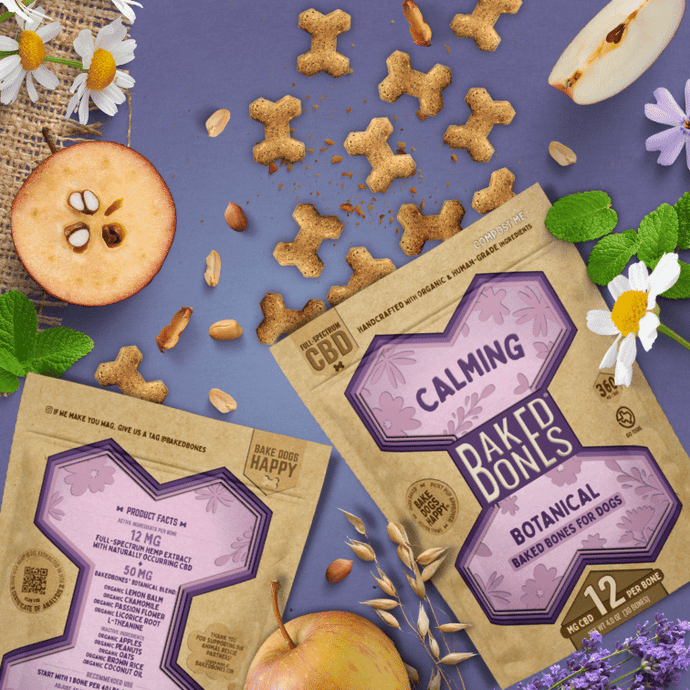 Busy image including golden-brown baked bones pouring out of two Kraft and purple bags of BakedBones, cut apples, chamomile flowers, shelled peanuts, lemon balm leaves, all against a purple background