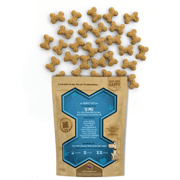Golden brown baked dog bones dotted with black chia seeds spilling out of a Kraft BakedBones bag with a blue bone and ingredients listed on the back