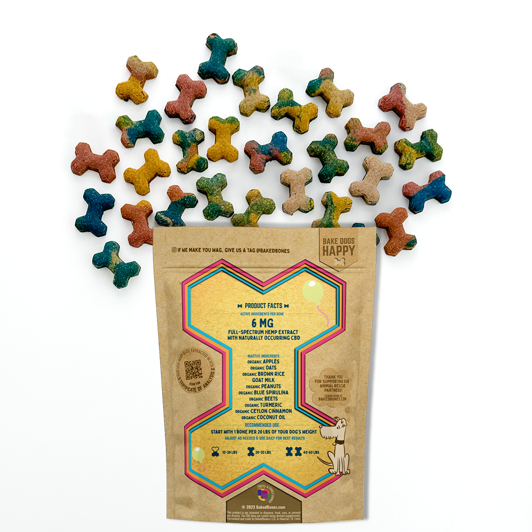 Baked dog bones of varying colors (red, blue, green, yellow, mixed) spilling out of a Kraft BakedBones bag with a pink/yellow/blue bone and ingredients listed on the back