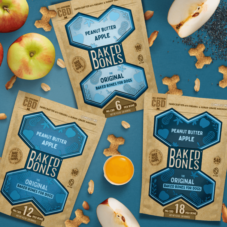 A busy image with 3 bags of Peanut Butter Apple BakedBones labeled 6 MG CBD, 12 MG CBD, and 18 MG CBD, all against a blue background and surrounded by apples, peanuts, eggs, and chia seeds
